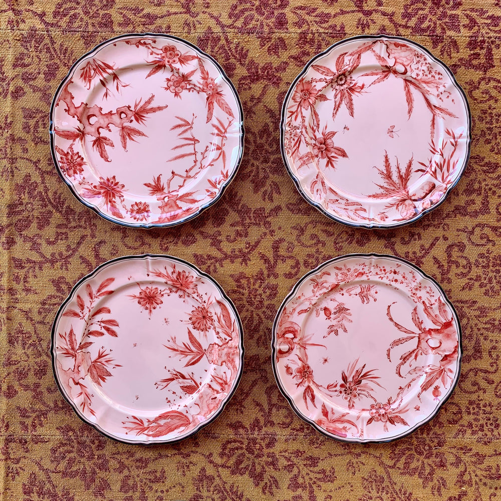 Top-down view of four Rocaille Pink dessert plates showing red floral transferware pattern and scalloped rims on woven fabric