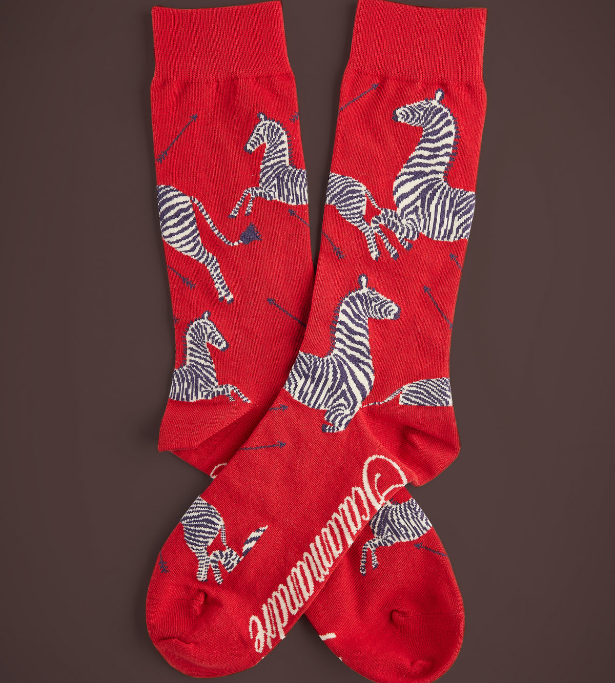 Close-up view of Men’s Zebras Socks showcasing red fabric and prancing zebra motifs against a brown background