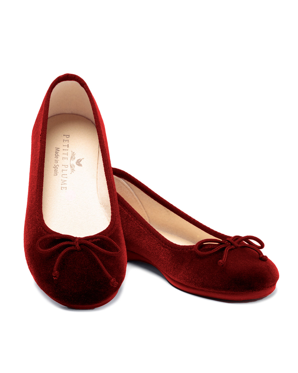 Angled view of The Juliette Ballet Slipper in Bordeaux Velvet showcasing velvet bows and soft insoles on a white background
