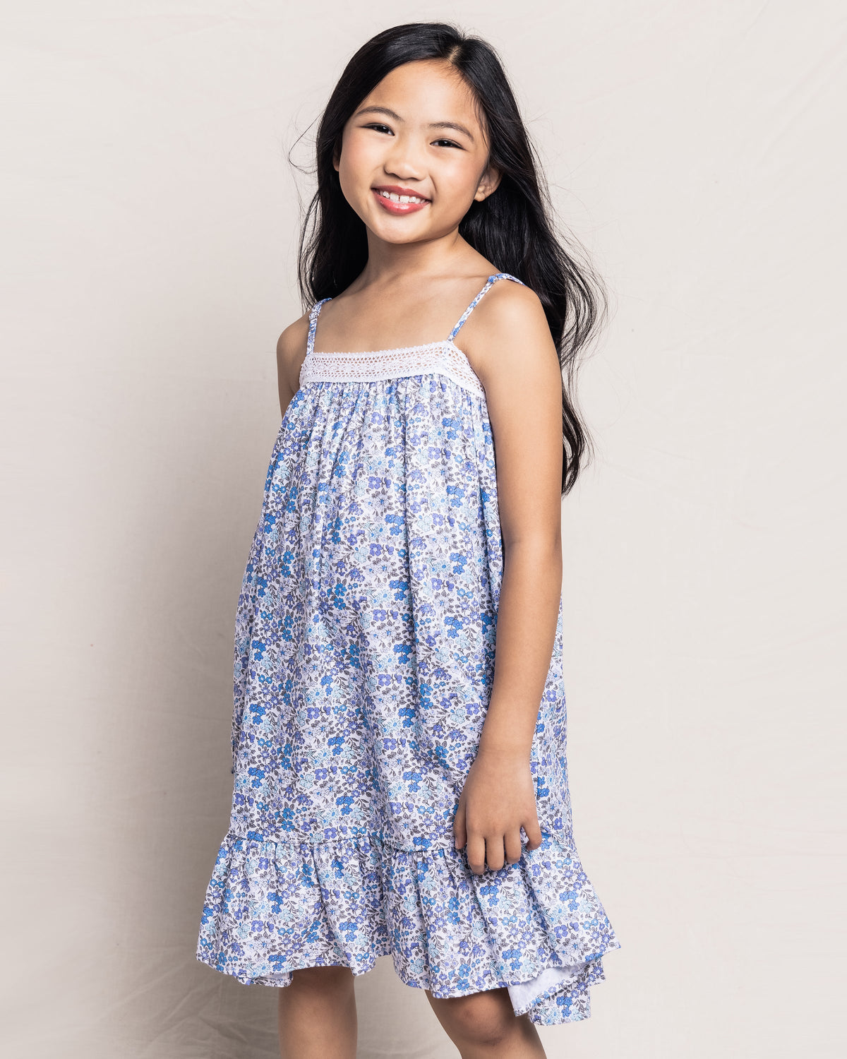 Front three-quarter view of Fleur D’Azur Lily nightgown on child showcasing blue floral print, lace neckline and ruffled hem