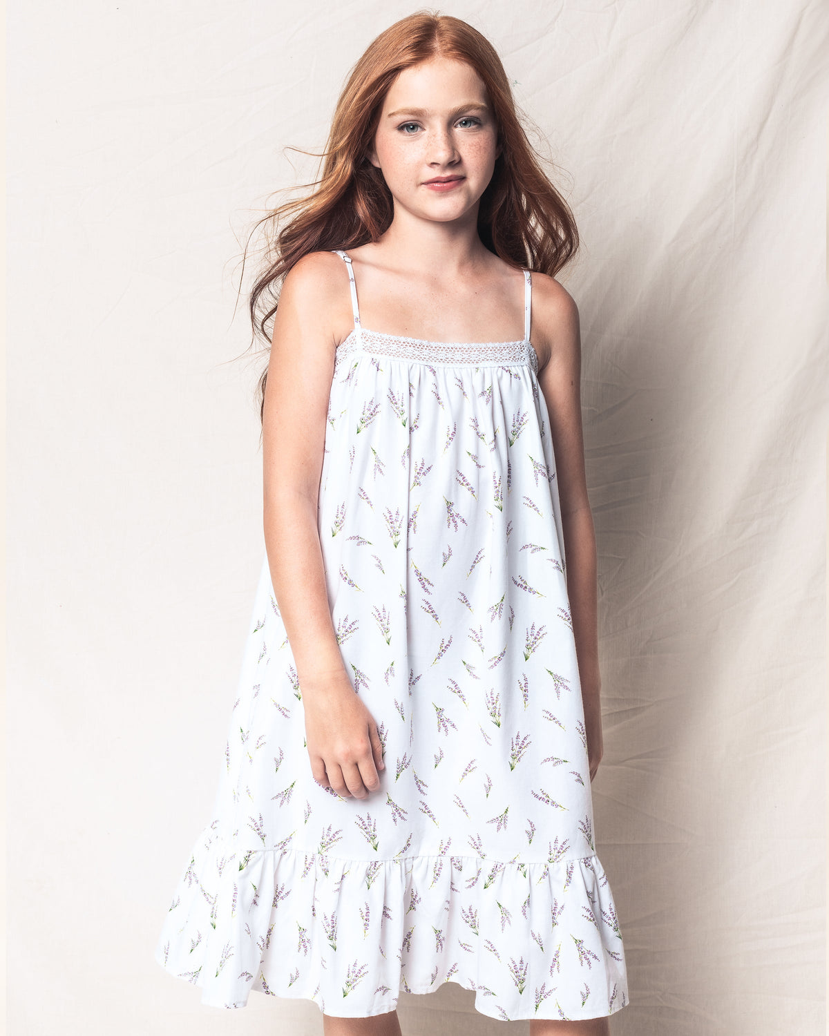 Front view of girls’ Fields of Provence Lily nightgown on model, lavender sprig print, lace trim, thin straps and ruffle hem