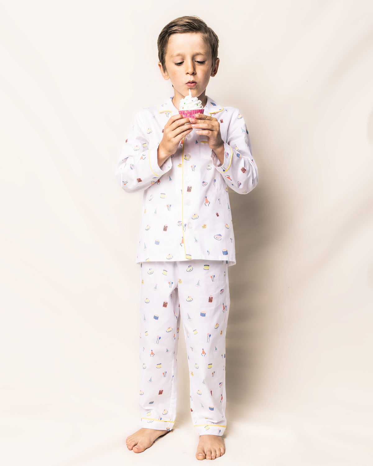 Front view of Children’s Birthday Wishes pajama set, white cotton top and pants with colorful print and yellow piping
