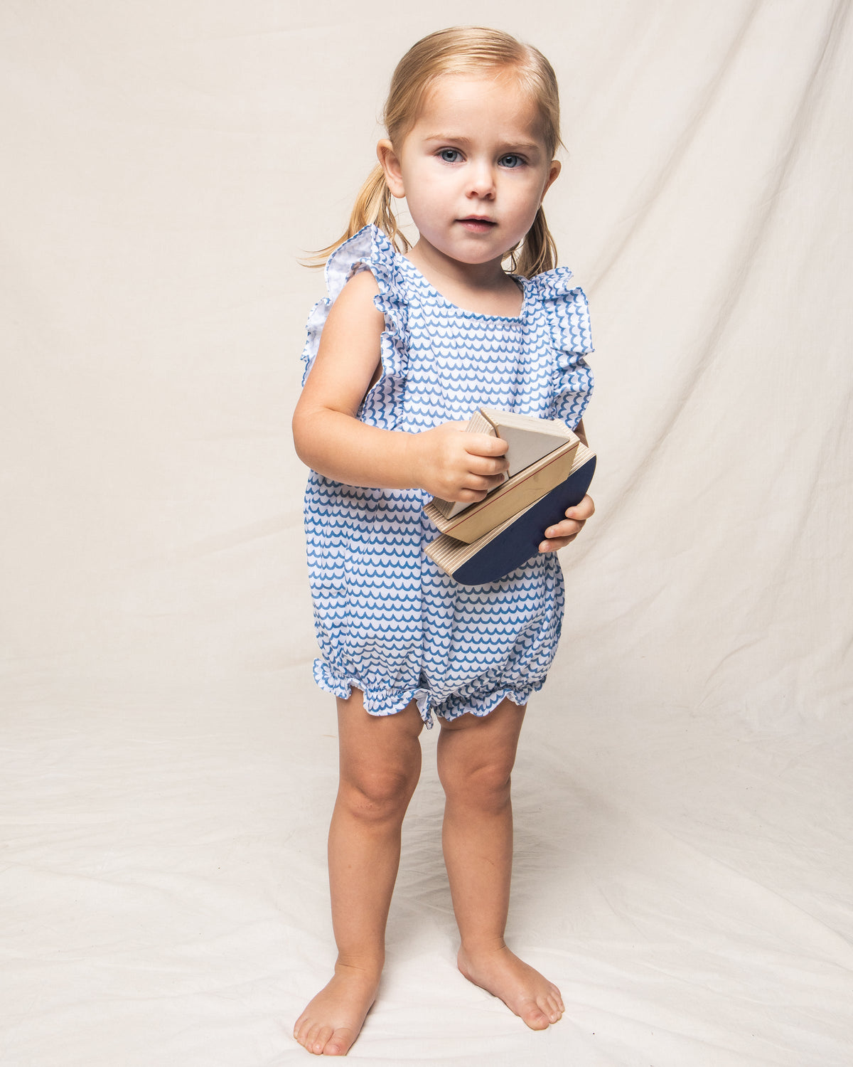 Front view of Children’s La Mer Ruffled Romper showcasing blue wave pattern and ruffled sleeves on a child against a white backdrop