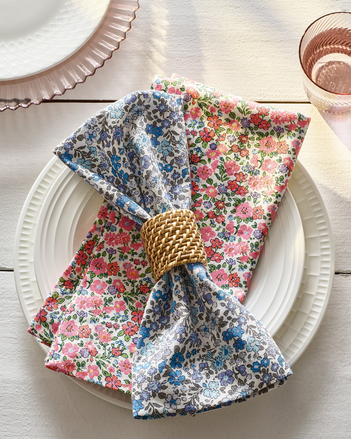 Styled view of Fleurs de Rose Napkins showcasing colorful hand-drawn floral prints on white plates