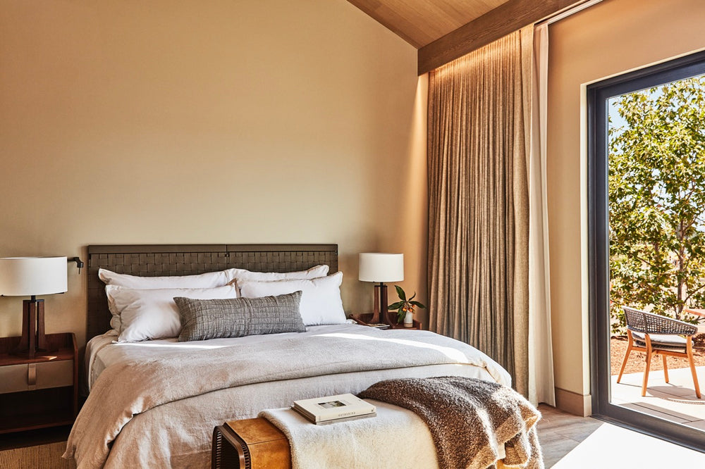 Angled view of Stanly Ranch king bedroom showcasing a king bed with layered neutral linens and a sliding glass patio door