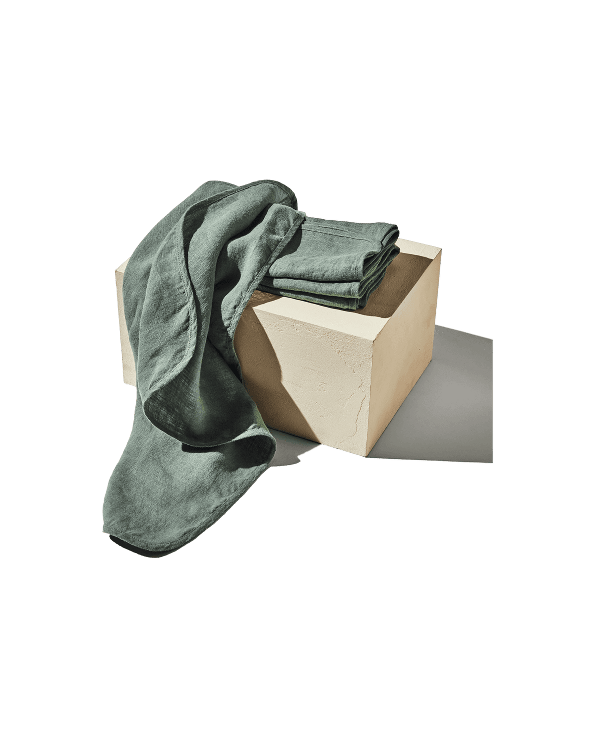 Front view of sage linen napkins, set of 4, showcasing stonewashed flax texture with a sculptural box background