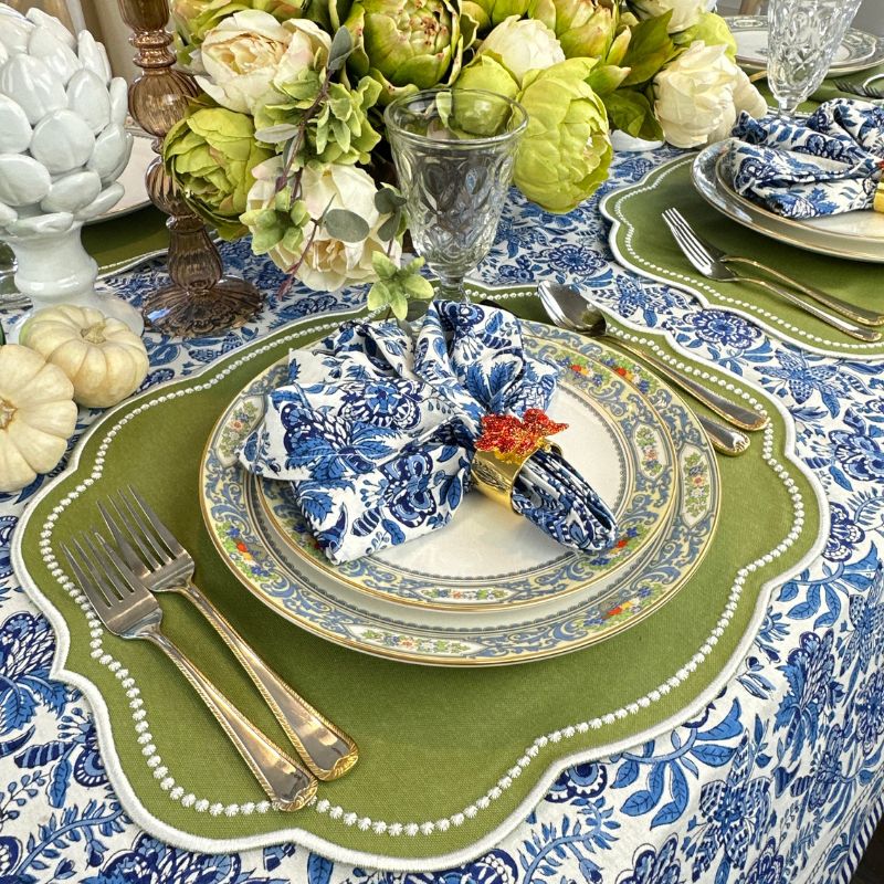 Sage placemat with white embroidery, blue floral tablecloth with matching napkin and leaf napkin rings