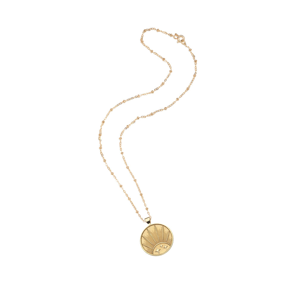 Flat lay of Strong Rising Sun small coin pendant necklace showing rising sun engraving on gold-dipped coin with beaded chain on white background