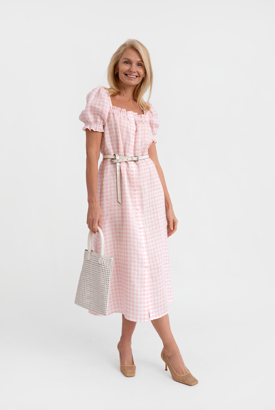 Front view of Brigitte midi dress in pink vichy showing ruffled neckline, puff sleeves and belt on white background