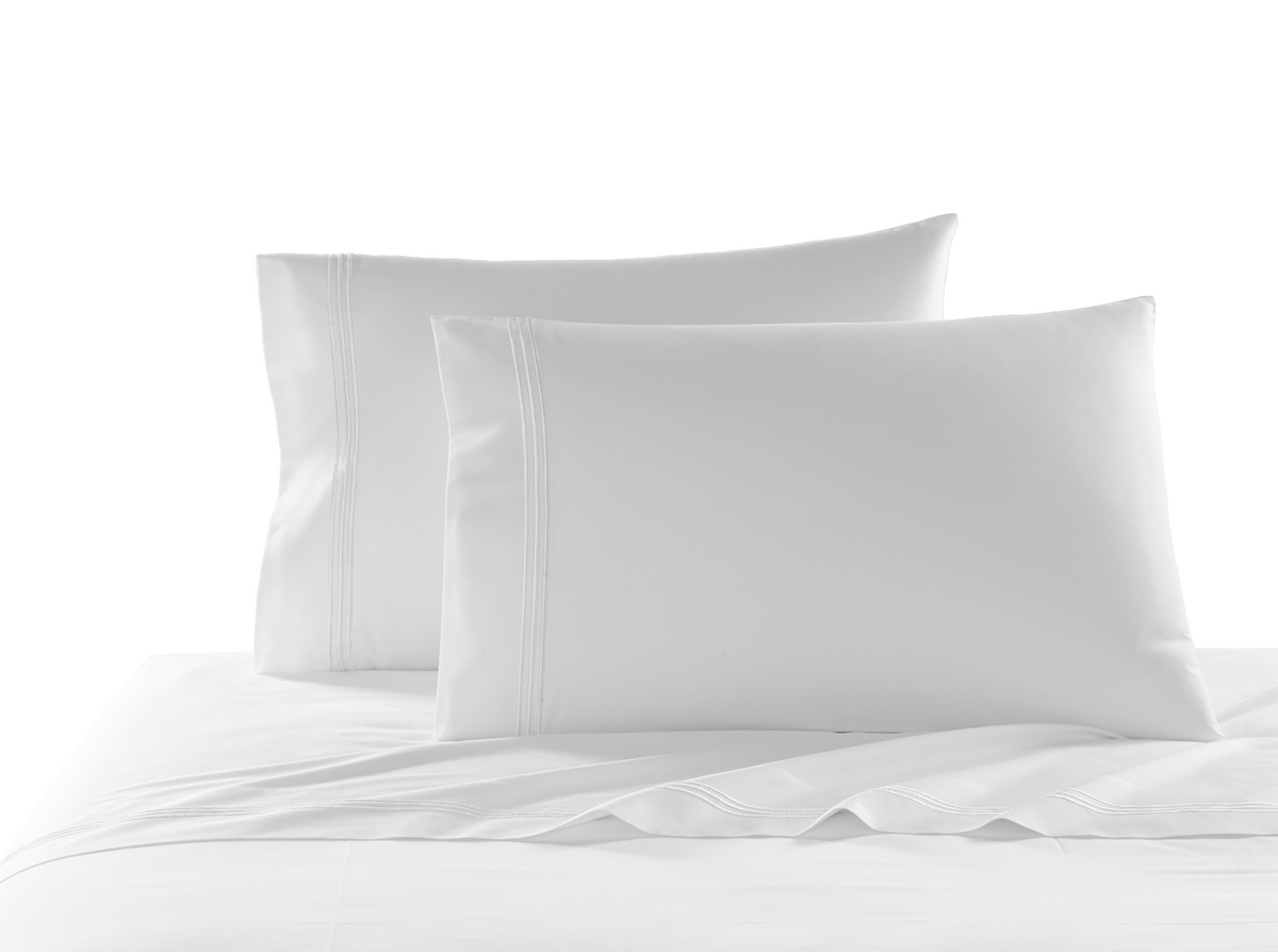 Angled view of Strada full fitted sheet showcasing white three-stripe embroidery on a made bed
