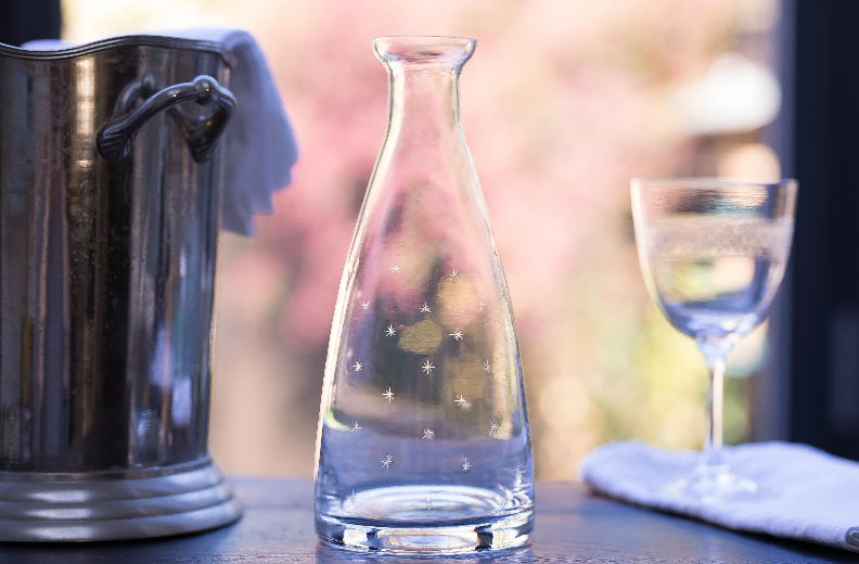 Front view of Crystal Table Carafe with Stars Design showcasing hand-engraved stars with a pitcher and wine glass background