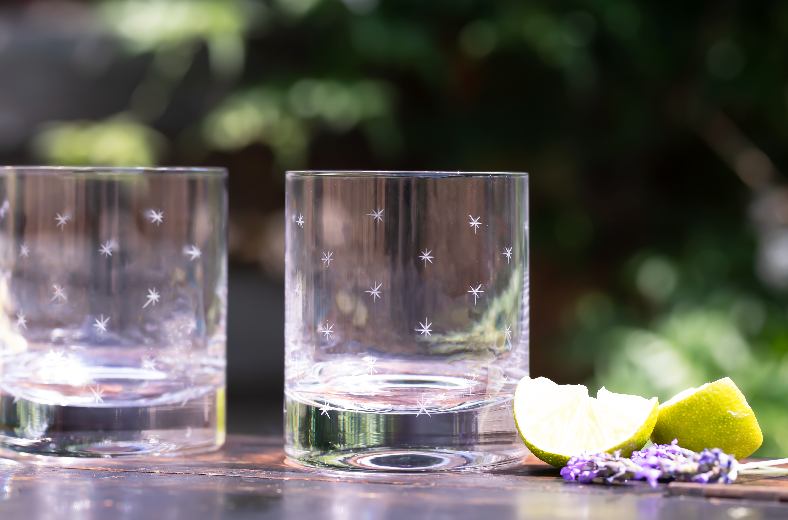 Front view of Pair of Crystal Whiskey Glasses with Stars Design showcasing engraved stars beside lemon wedges