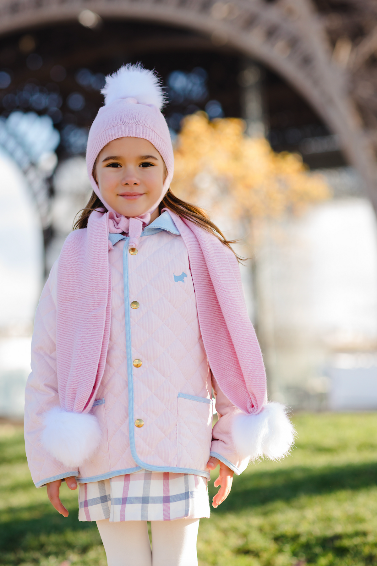 Front view of the Classic Pink Quilted Jacket showcasing diamond quilting, blue trim, and gold snaps on a child outdoors