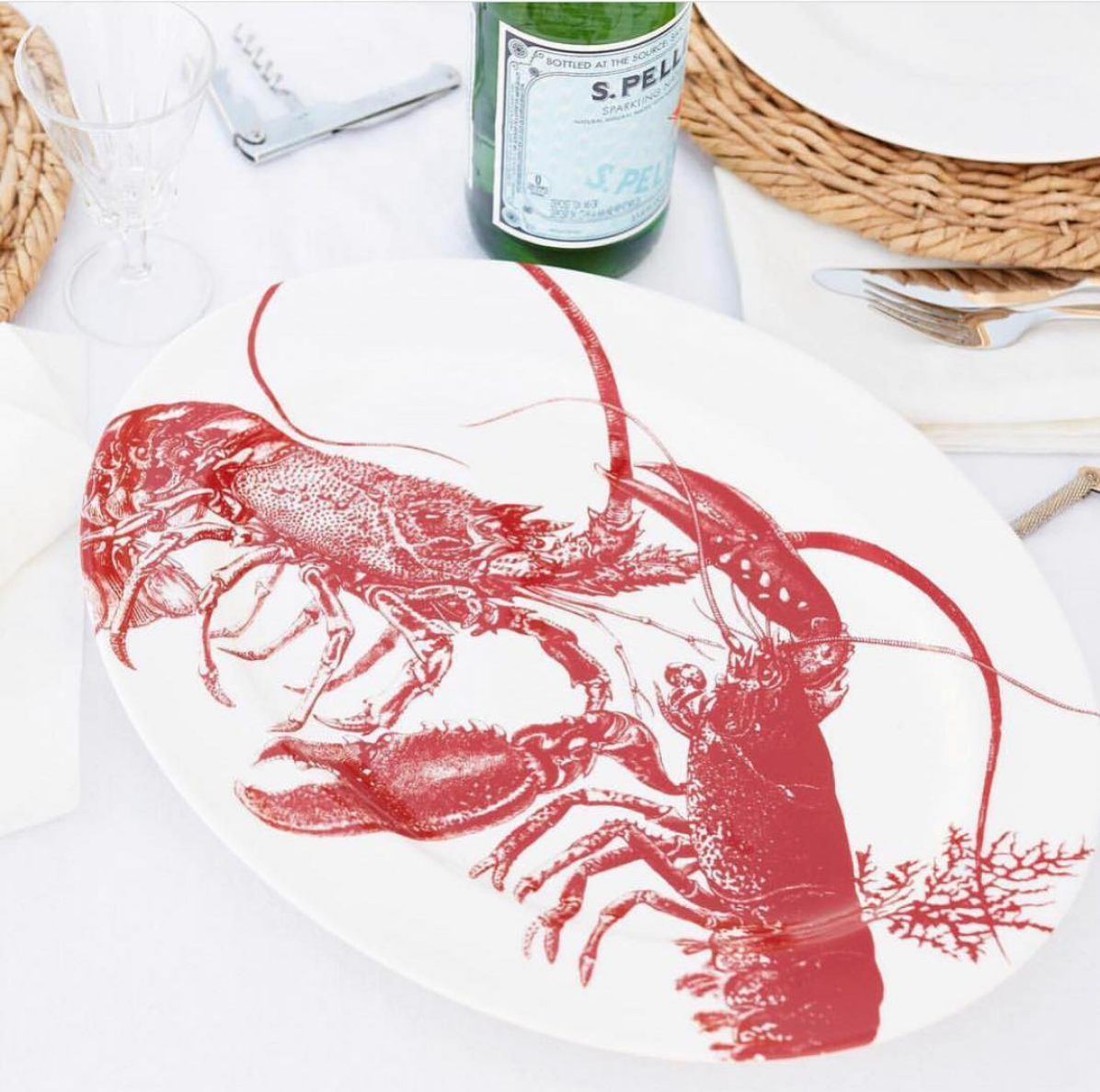 Angled view of Red Lobster Large Oval Rimmed Platter showcasing red lobster artwork on white porcelain with a table setting