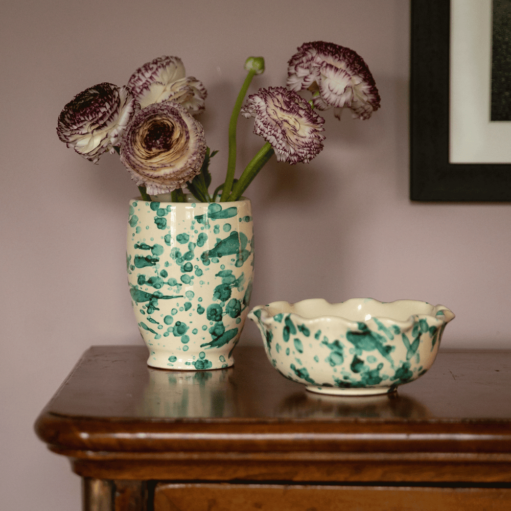 Front view of Splatter Bambino vase showing green splatter pattern on cream ceramic with ranunculus flowers on a wooden table