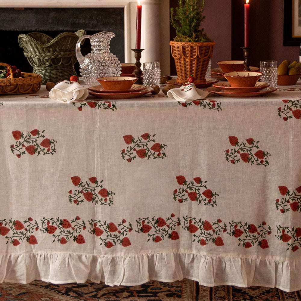 Front view of Fraises Des Bois tablecloth showcasing hand-blocked strawberry motif and ruffle hem on a set dining table