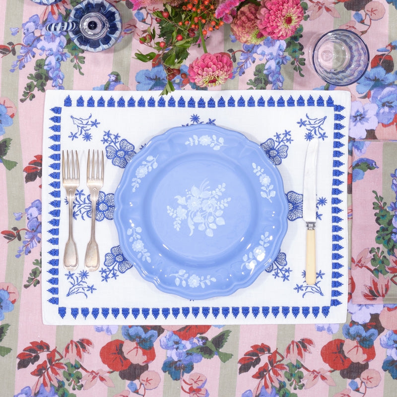 Top view of Sicilia Periwinkle Dinner Plate showcasing white hand painted floral motif and scalloped edge with floral place setting