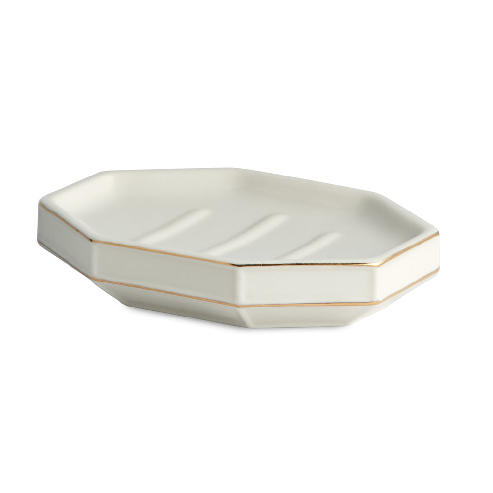 Angled view of St. Honore soap dish with hexagonal porcelain form, gold rim accents and three drainage grooves on white