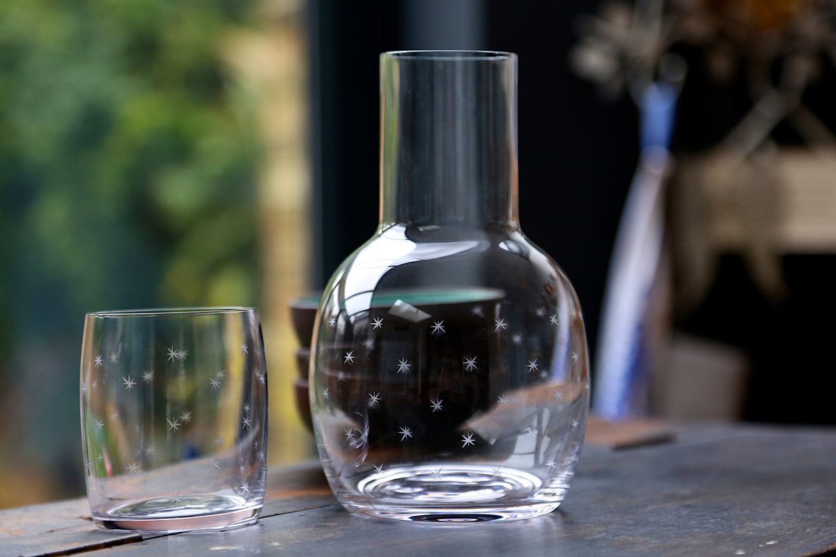 Front view of crystal carafe and glass set showcasing engraved star pattern on a tabletop