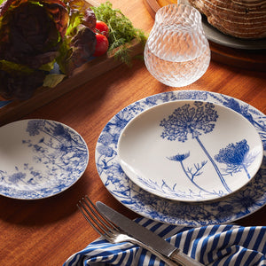 A set of Summer Blues Coupe Salad Plates adorned with Queen Anne's lace on a wooden table by Caskata Artisanal Home.