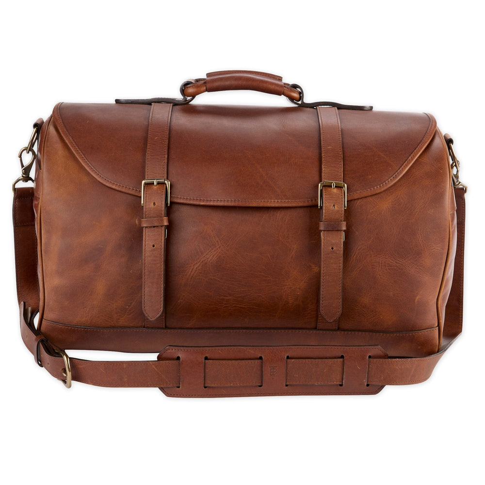 Front view of oak leather weekender duffel bag with brass hardware, rolled handle and adjustable shoulder strap