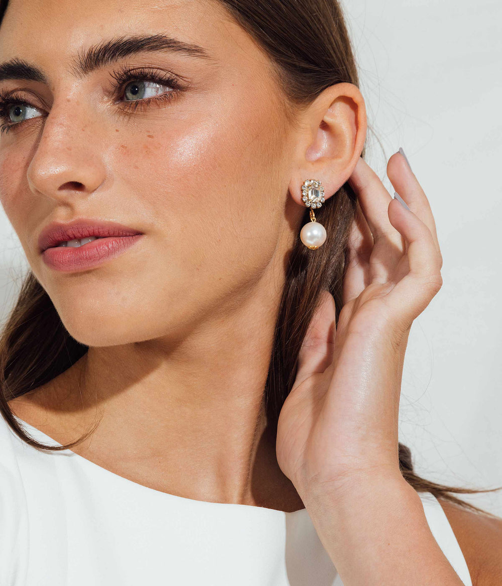 Close-up of model’s right ear wearing Tatiana Pearl Earrings with crystal-studded gold stud and dangling glass pearl against white background
