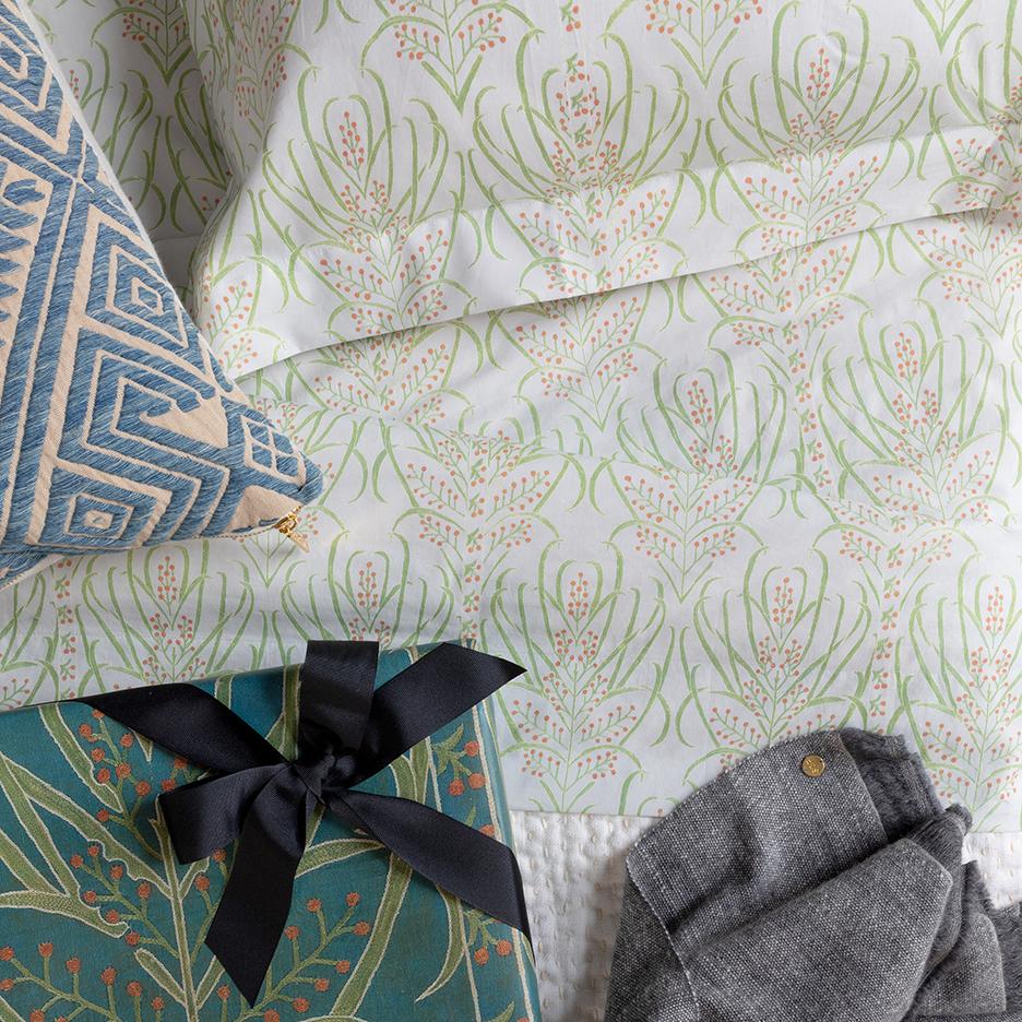 Close-up of Vines Suzani Duvet in Light Teal showcasing green botanical pattern with folded textiles
