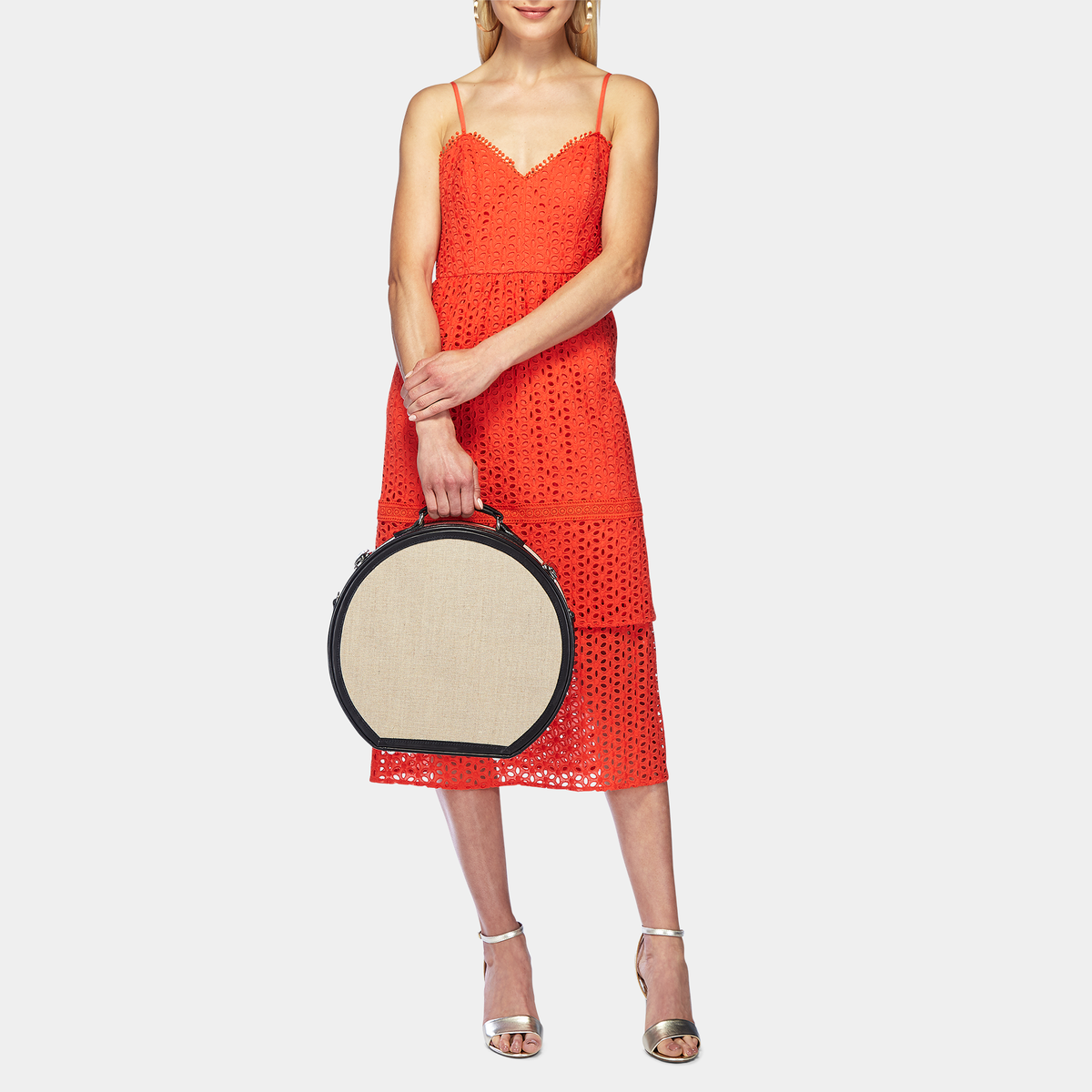 Front view of The Editor in Black Hatbox Large showcasing its ivory body and black straps with a model in a red dress