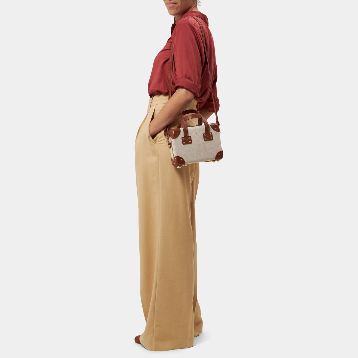 Side view of The Editor in Brown Mini showcasing ivory body and brown leather straps on model against light gray background
