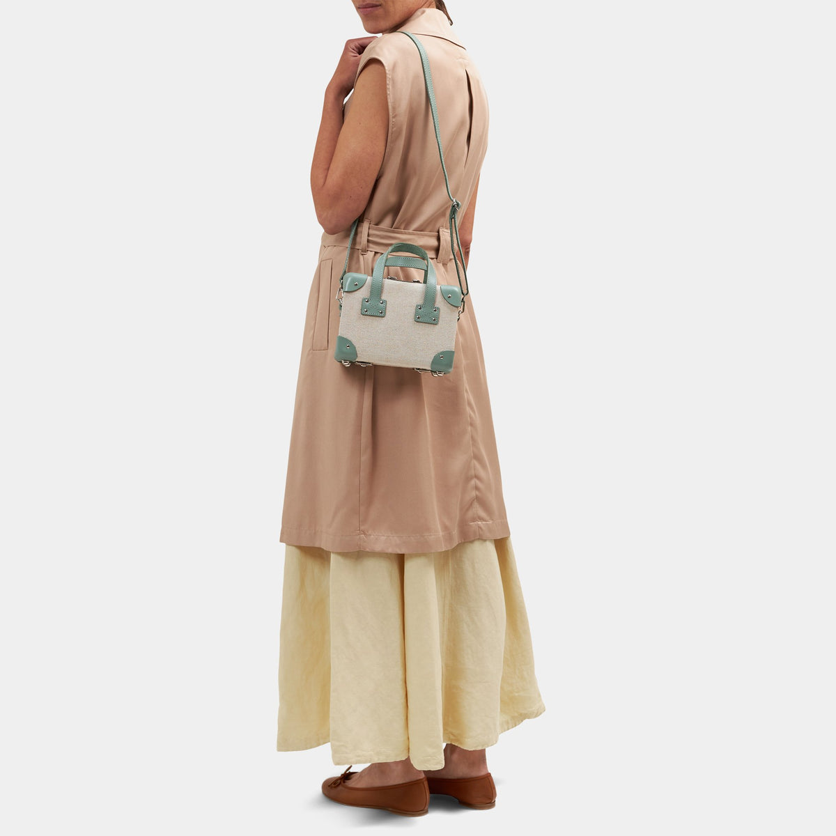 Rear view of The Editor Mini showcasing its ivory body and sea green leather strap on a model against a light gray background