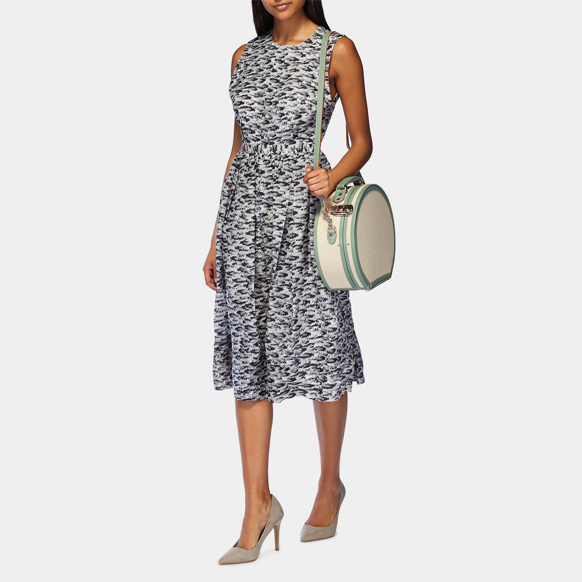 Front view of The Editor small hatbox showcasing ivory body, sea green straps, and silver latches with a model carrying it