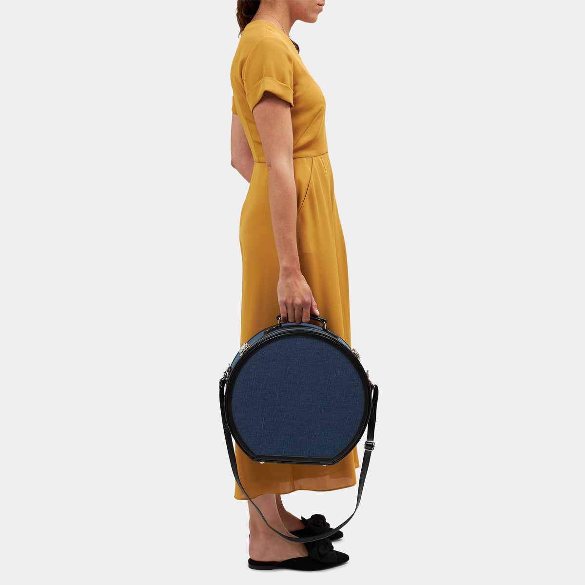 Side view of The Editor Large Hatbox showcasing navy body and detachable straps on a light gray background