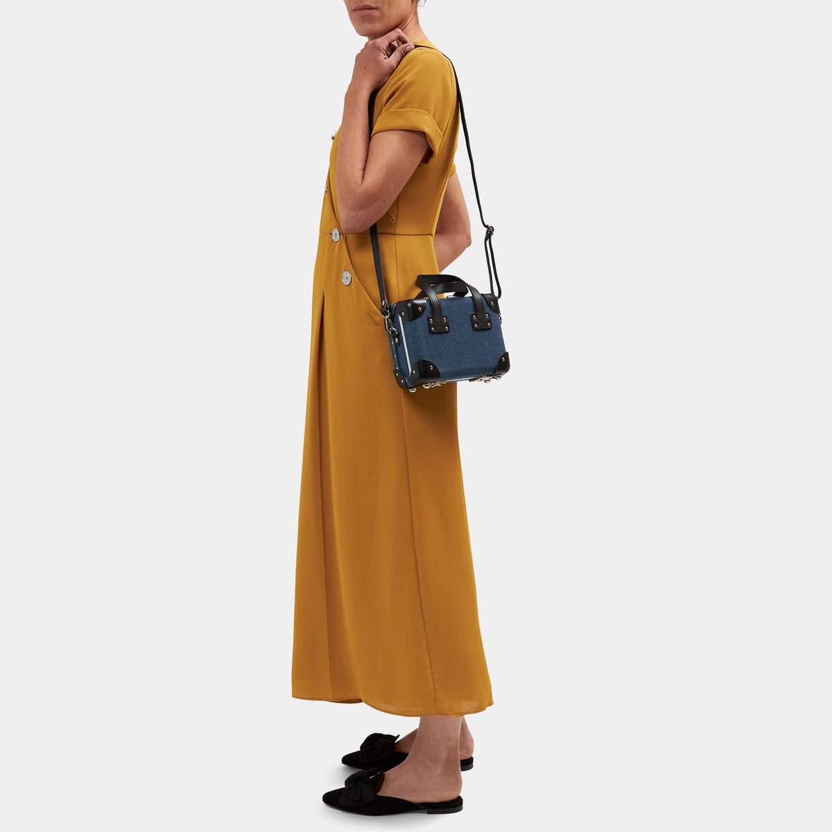 Side view of The Editor in Navy Mini showcasing navy linen and black leather straps on model against light gray background