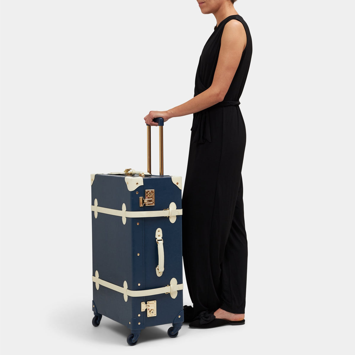 Front view of The Entrepreneur Check In Spinner showcasing navy vegan leather, white straps, and extendable handle with model