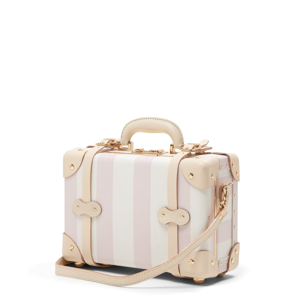 Three-quarter view of The Illustrator Pink Vanity suitcase with pink-and-white stripes, tan leather trim and gold hardware