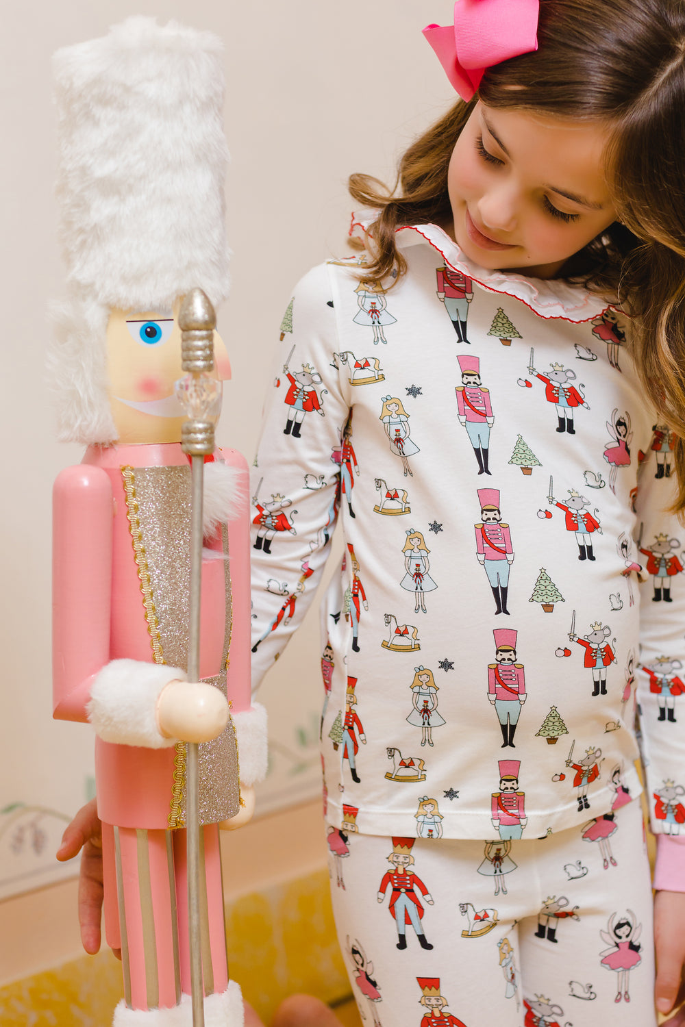 Right-side view of girl’s Nutcracker print pajama set showcasing allover holiday characters and ruffled collar on a pale background