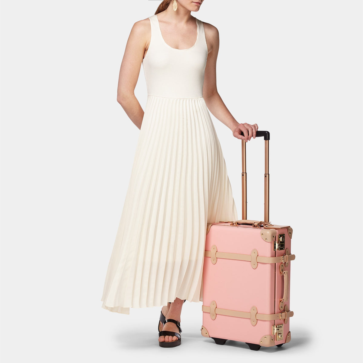 Front view of The Correspondent Pink Carryon showcasing tan leather straps and gold hardware with a model on a light background