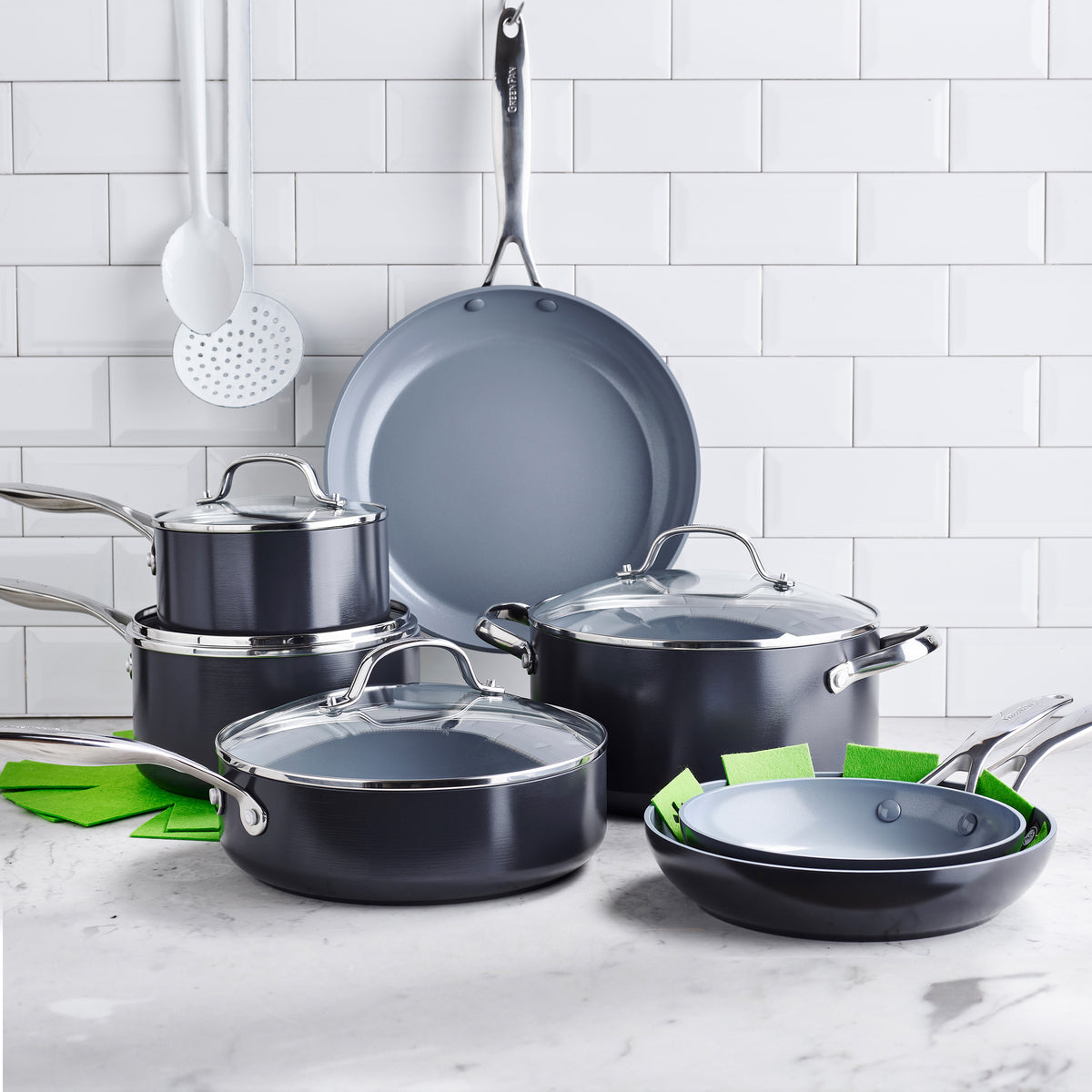 Front view of Valencia Collection Cookware 11-Piece Set in Black showcasing pots, pans, and glass lids with white tile background