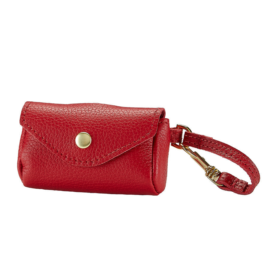 Front view of pet waste bag holder in red pebble-grain leather showing snap-flap opening and antique brass clip on white background