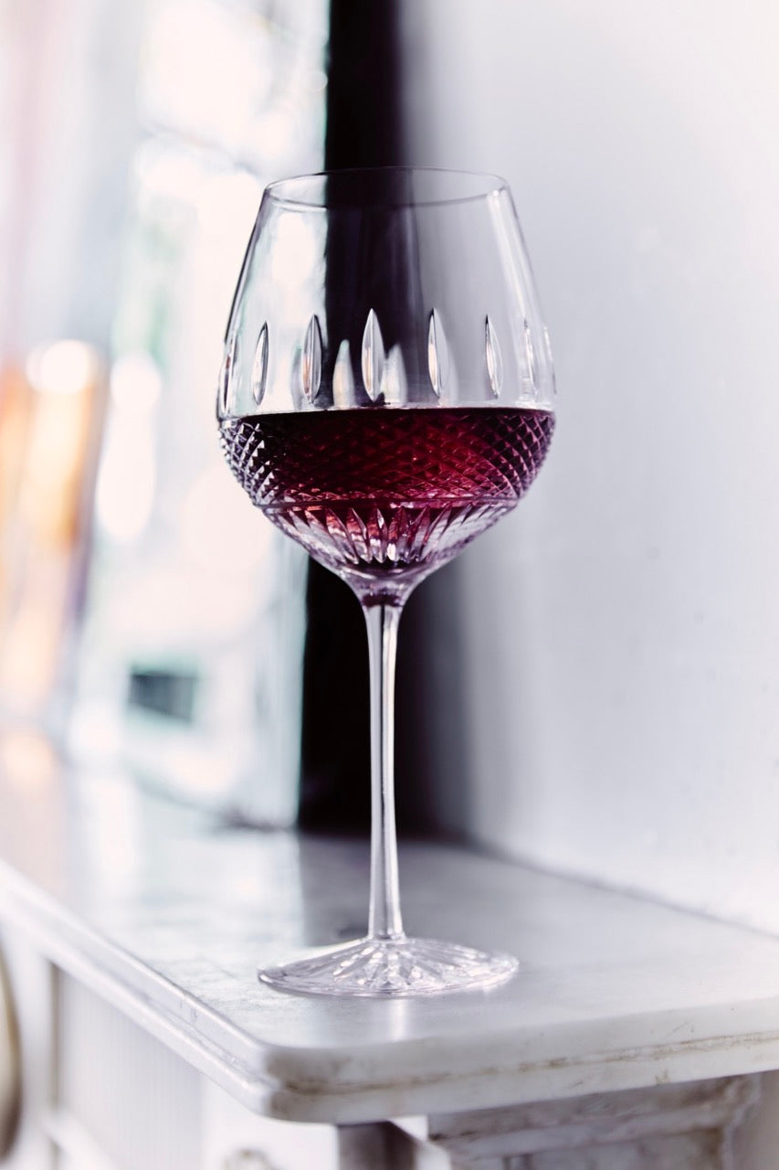 Close up view of Irish Lace red wine glass showcasing diamond and wedge cut crystal bowl and long stem on marble mantel