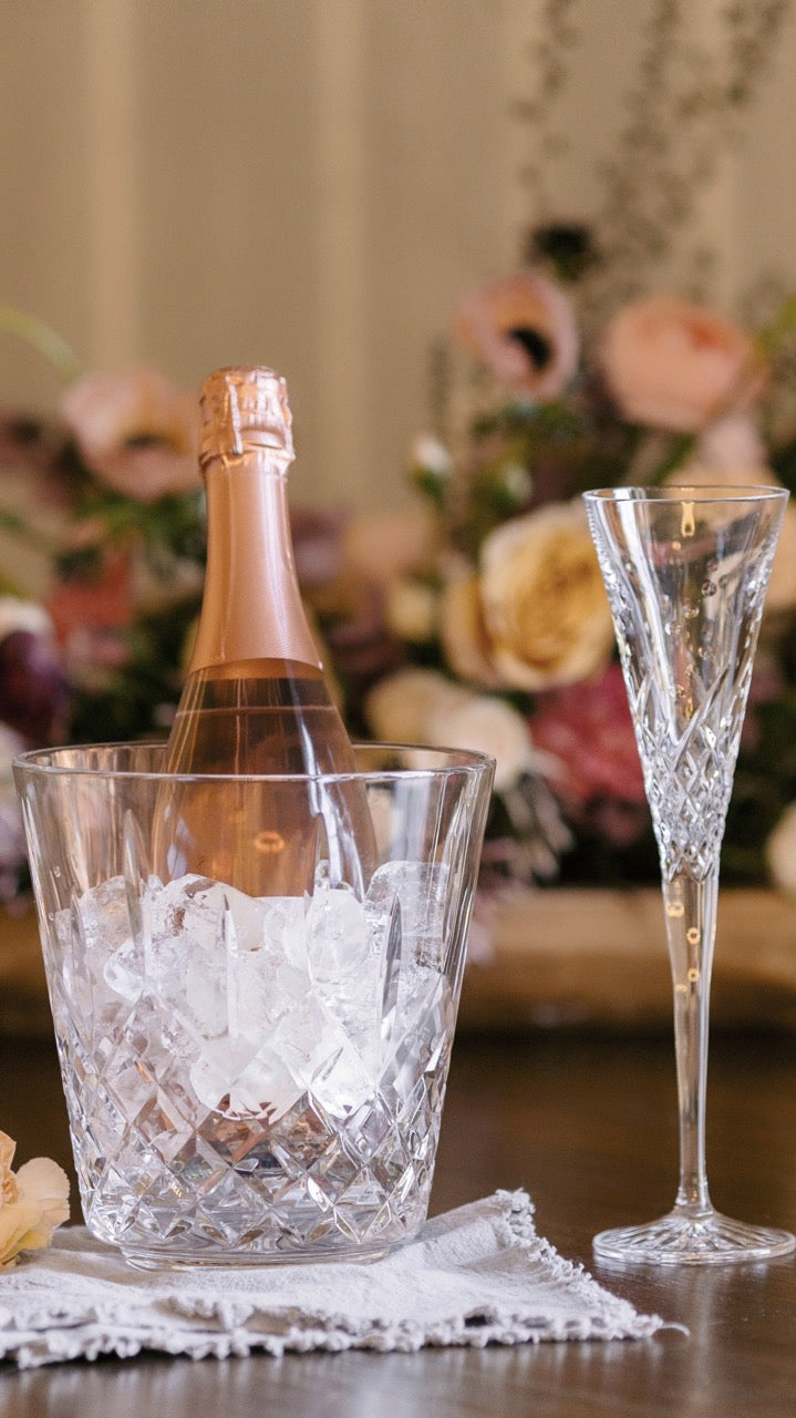 Front view of Lismore crystal ice bucket with diamond-and-wedge cuts holding ice and a rosé bottle on a wooden table