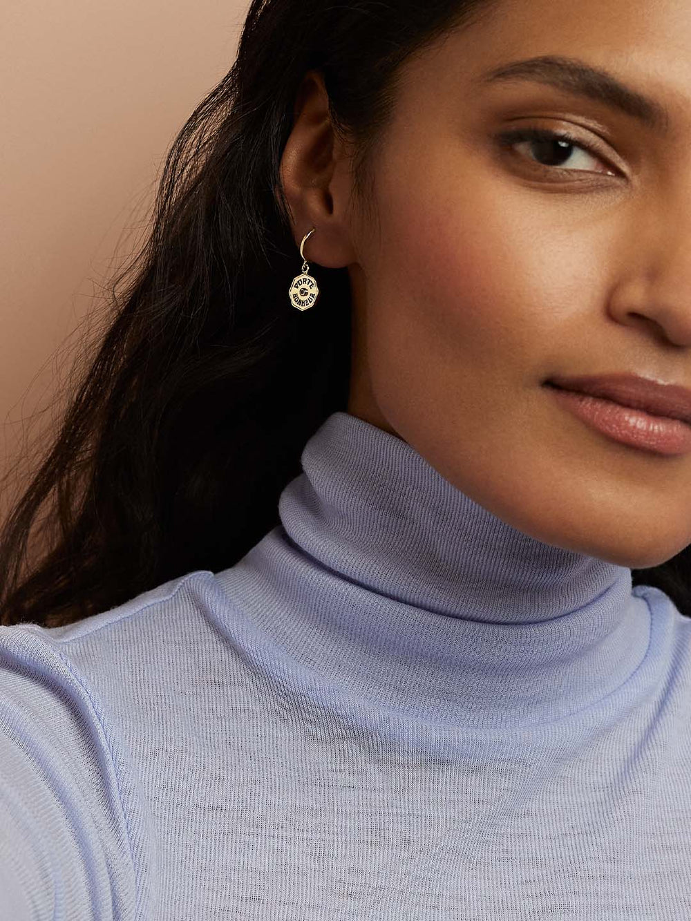 Close-up of model’s ear wearing Wee PB Hoops White Diamond, gold huggie with dangling PORTE BONHEUR coin and diamond