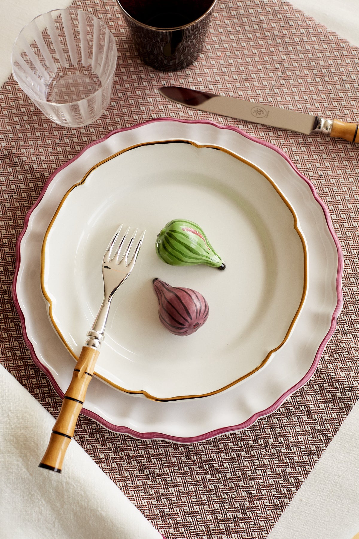 Top-down view of Trompe L’œil Figue decorative plate showing painted trompe l’œil figs, gold-leaf inner rim, and pink scalloped edge
