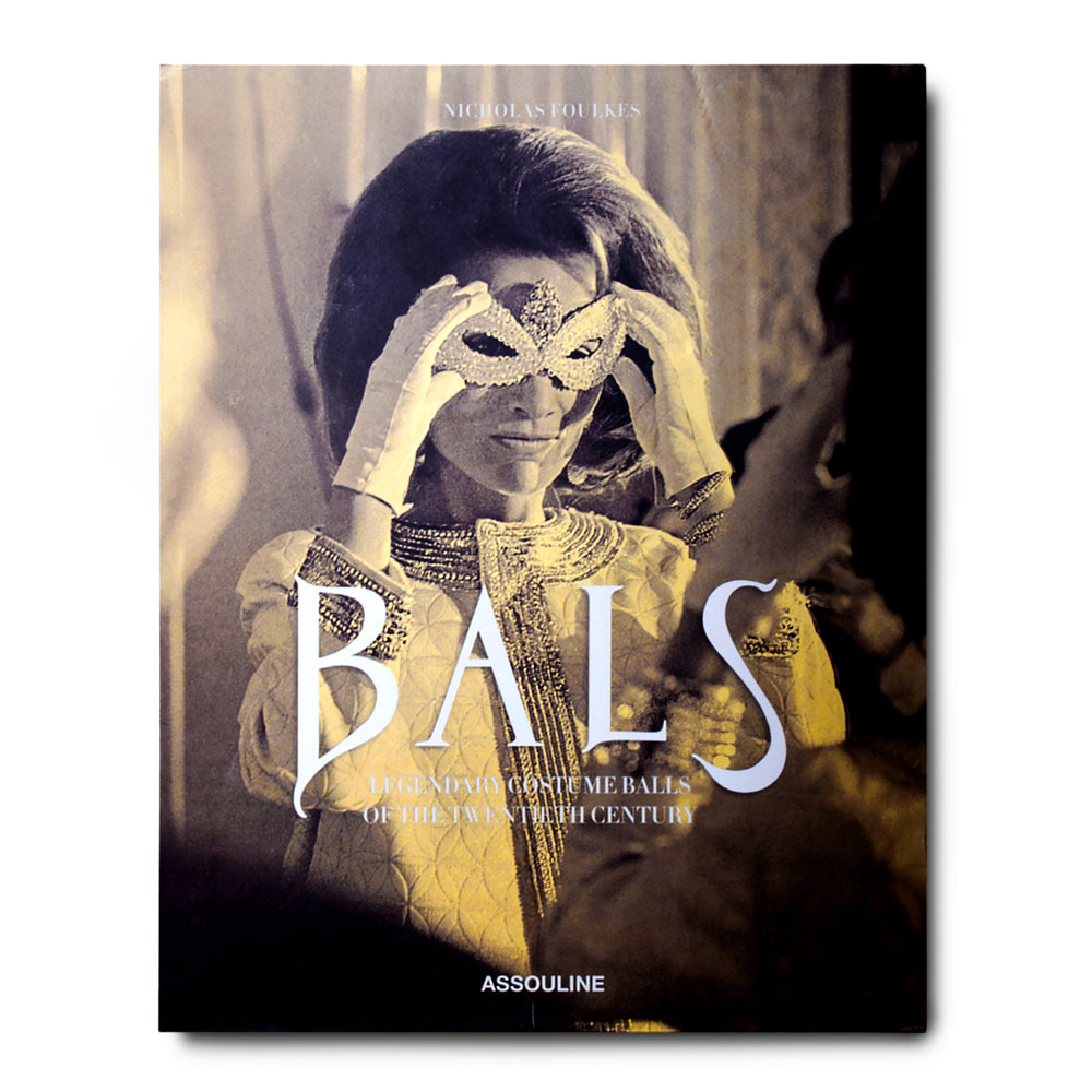 Front of Bals hardcover slipcase showing a woman adjusting a beaded mask on a gold-toned cover with large title text BALS