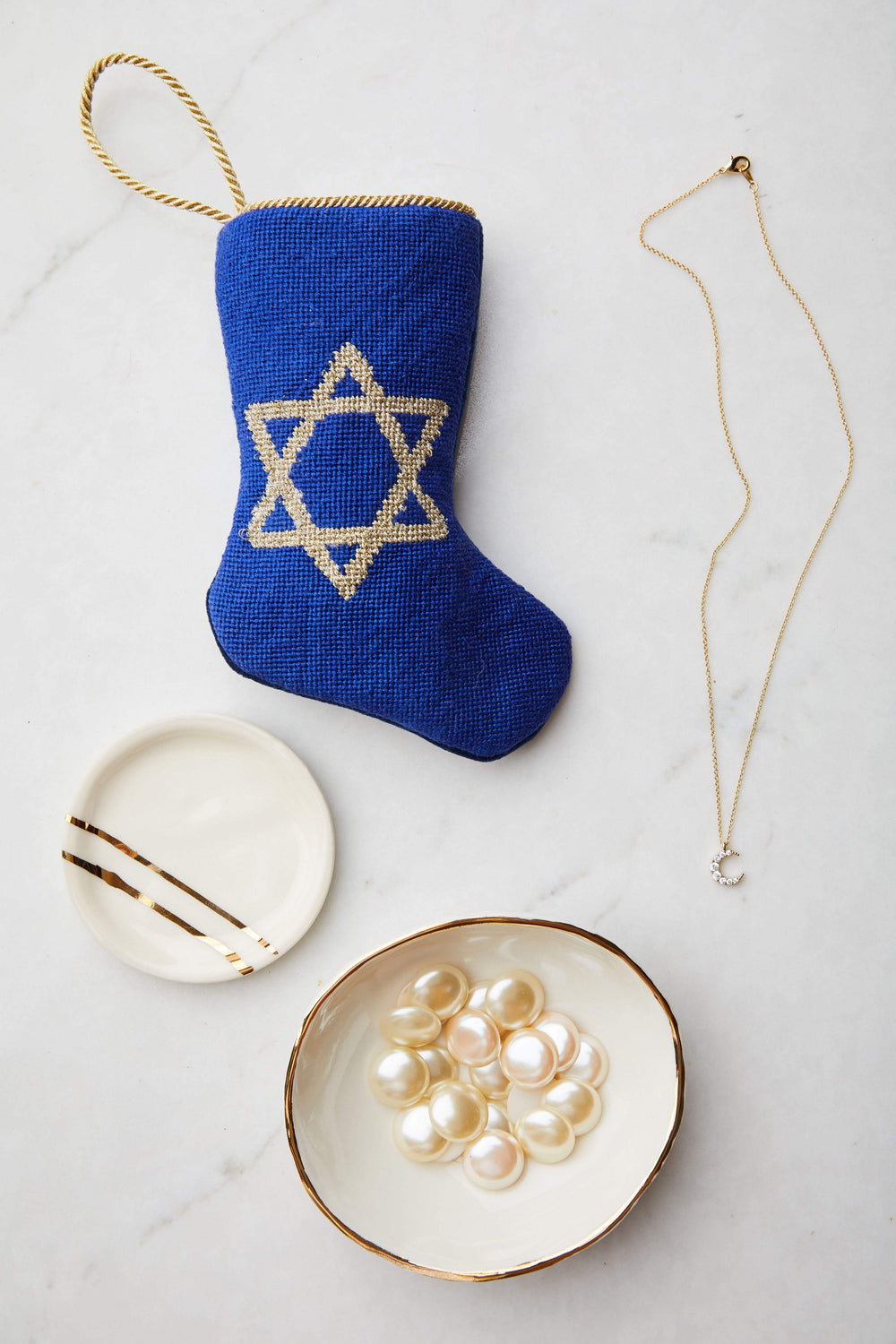 Top-down view of Star of David bauble stocking showcasing gold needlepoint star on royal blue fabric with marble background