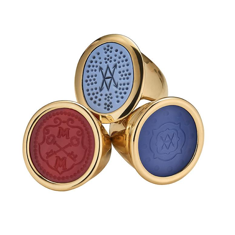 Three-quarter view of ASHA Large Bespoke rings showcasing 18K gold bands with red and blue engraved intaglio faces on white background