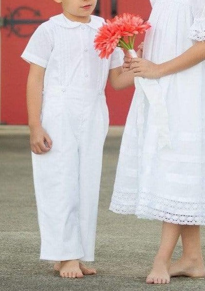 Full-length front view of Boys Bobbie suit showcasing short sleeves, Peter Pan collar, and matching long pants with gray outdoor ground and red door background