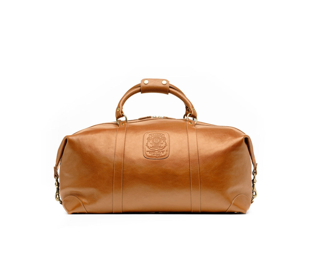 Front view of Cavalier II No. 97 duffel in vintage tan leather with top handles, embossed logo and brass hardware on white