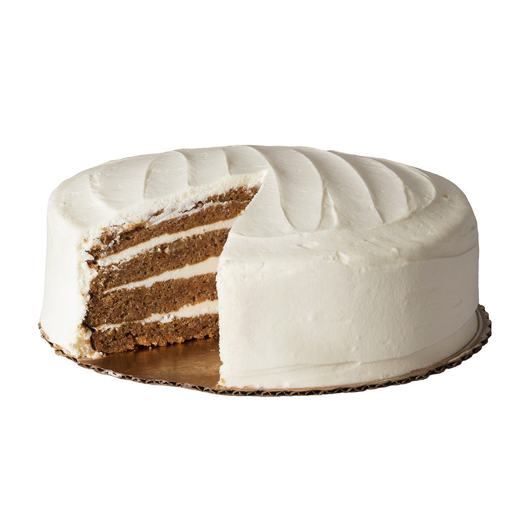 Angled view of Traditional Carrot Cake showing four layers of carrot cake and cream cheese icing with one slice removed on white background