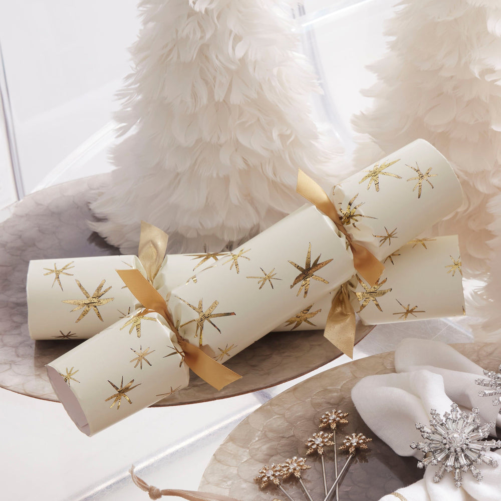 Three-quarter view of Luxury Celebration Crackers in cream showcasing gold foil star print and gold ribbon, arranged on a decorative platter
